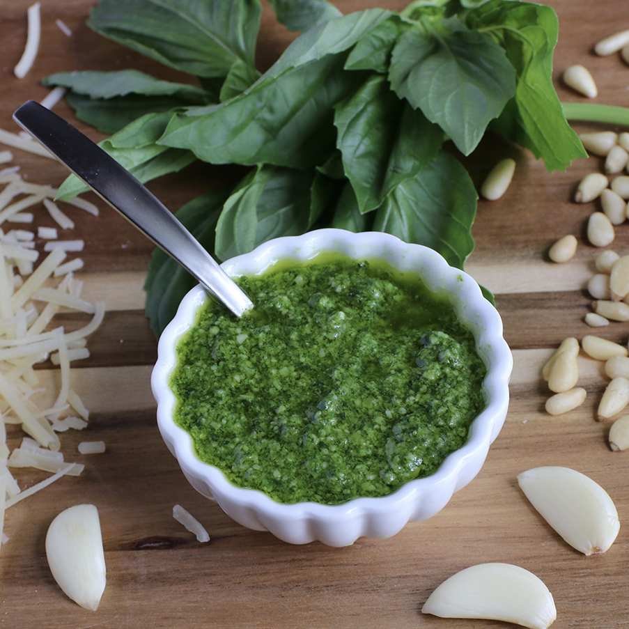 Een bakje pesto met ingrediënten ernaast