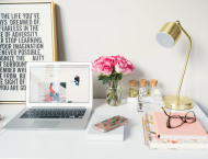 Een bureau met een laptop, een lamp, notitieblokken en meer